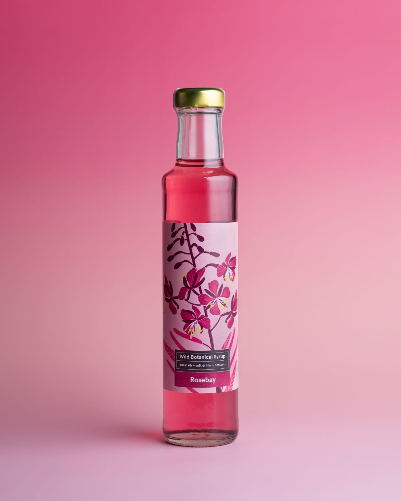 Bottle of pink liquid with a floral label on a pink background